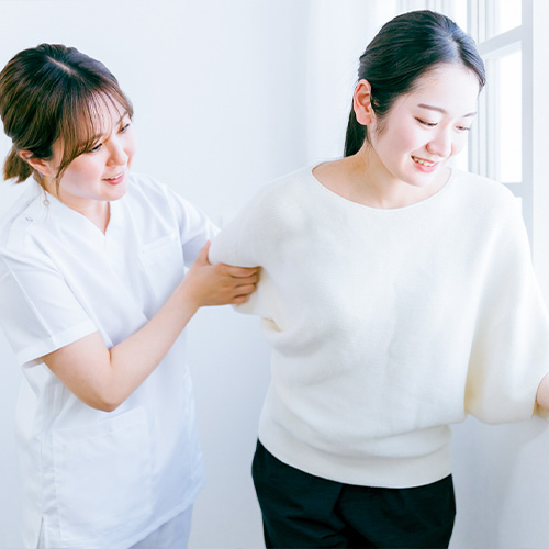 車いすの女性の手を握る介護士